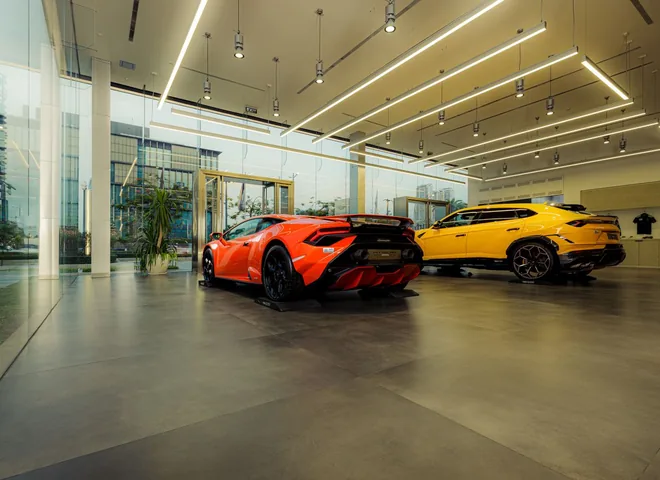 Sports cars displayed in a spacious glass-walled dealership showroom