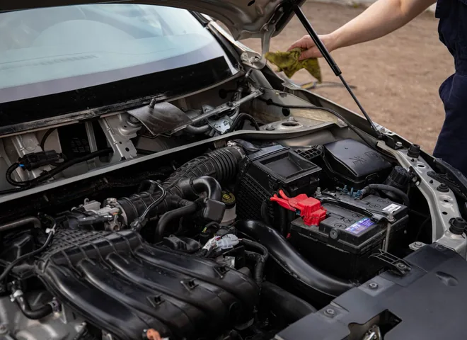 Mechanic checking the engine bay of a car with the hood open